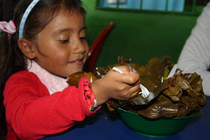 Foto de una niña comiendo tamal